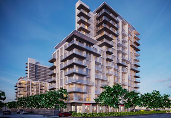 A modern multi-story residential building with balconies and trees in front.