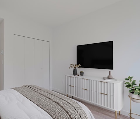 A modern bedroom with a large bed and a flat screen TV on a white radiator.