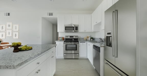 a white kitchen with stainless steel appliances and marble counter tops