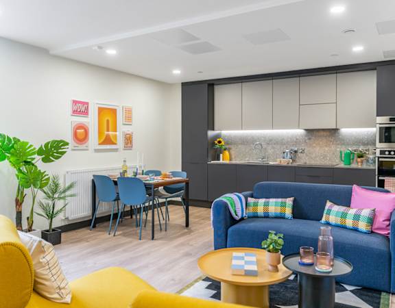a living room with a blue couch and a kitchen with a table and chairs