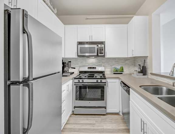 A modern kitchen with a refrigerator, stove, and microwave.