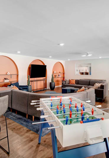 a living room with a table and chairs and a game table in the middle