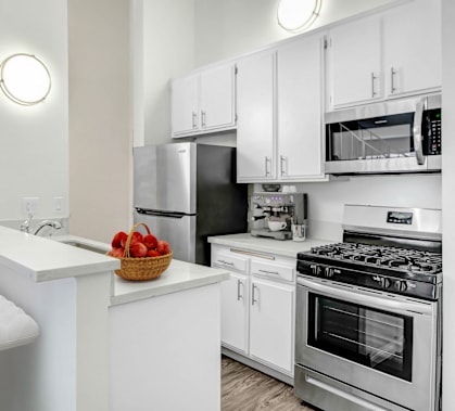 an apartment kitchen with stainless steel appliances and white cabinets