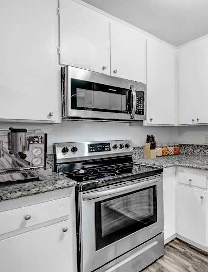 A kitchen with white cabinets and a granite countertop.