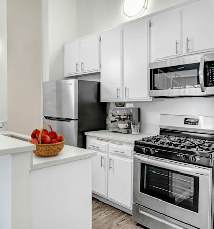 an apartment kitchen with stainless steel appliances and white cabinets