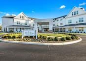 Thumbnail 5 of 5 - a roundabout in front of a large building with a sign for the residence hall at White Springs Senior Living, Warrenton, Virginia
