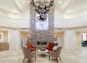 Thumbnail 3 of 5 - a living room with a fireplace and a chandelier at White Springs Senior Living, Warrenton, VA