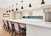 Thumbnail 1 of 5 - a kitchen with a large white counter top and chairs at White Springs Senior Living, Virginia 20186