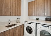 Thumbnail 8 of 51 - A modern laundry room with a washer and dryer.