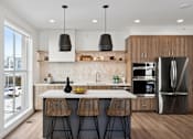 Thumbnail 27 of 51 - A modern kitchen with a white countertop and wooden chairs.