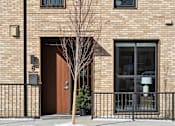 Thumbnail 22 of 51 - A brown door with a window above it and a tree in front of it.
