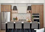 Thumbnail 19 of 51 - A modern kitchen with a white countertop and grey chairs.