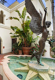 A statue of a bird is in front of a fountain.