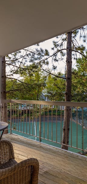 A balcony with a chair and a view of a pool and trees.