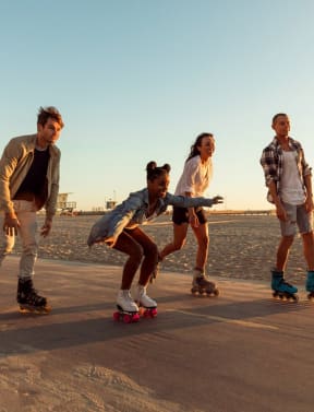 a group of people riding skateboards on the beach