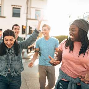 A group of people are walking down a street with their arms in the air.