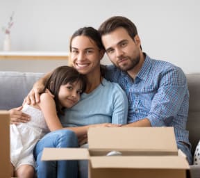 a family sitting on a couch with a cardboard box in front of them