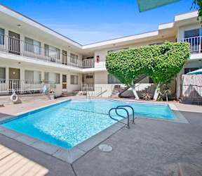 A pool in a courtyard surrounded by a white building.