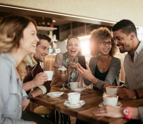 a group of people sitting around a table talking and laughing