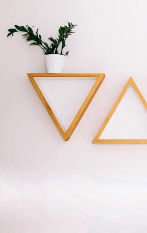three triangles hanging on a wall with a plant