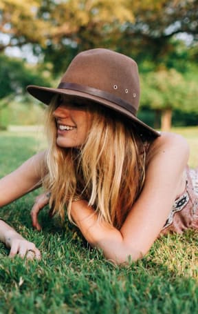 a woman laying in the grass with her dog