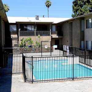 A black fence surrounds a small pool in a courtyard.