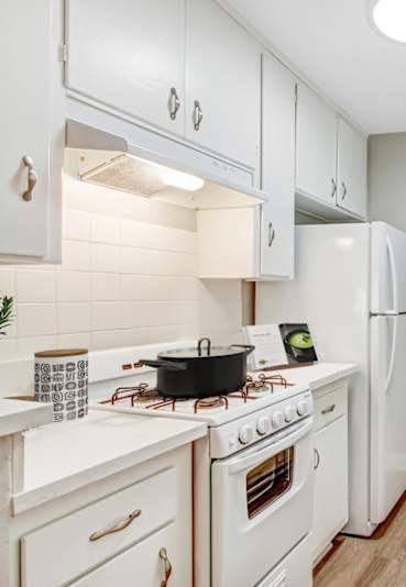 A white kitchen with a stove, sink, and refrigerator.