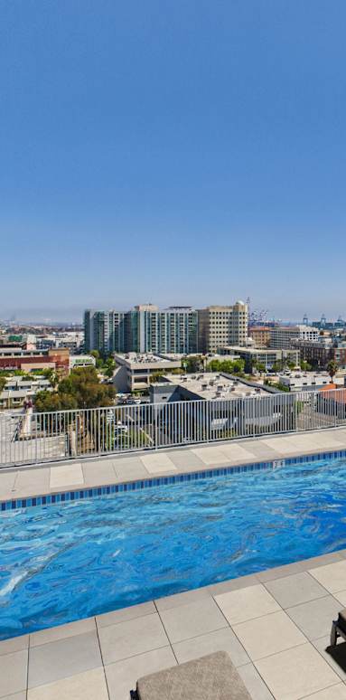 A row of sun loungers are on the edge of a pool.