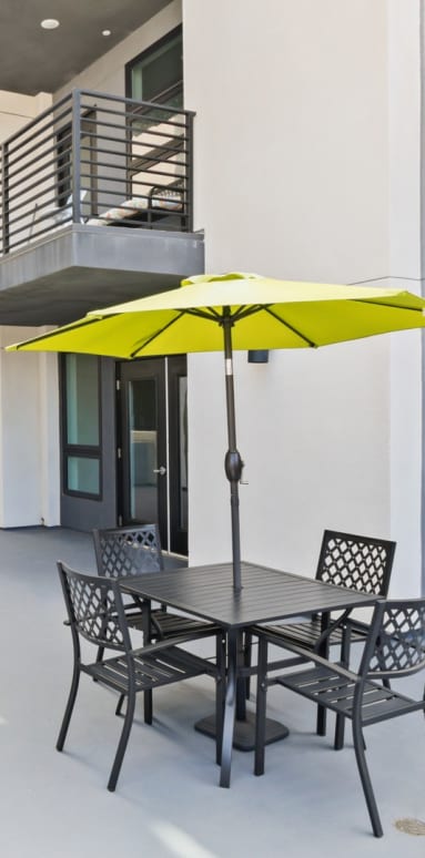 a patio with a table and chairs and a yellow umbrella