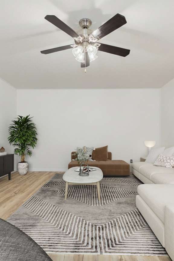 A living room with a white couch, a wooden floor, and a ceiling fan.
