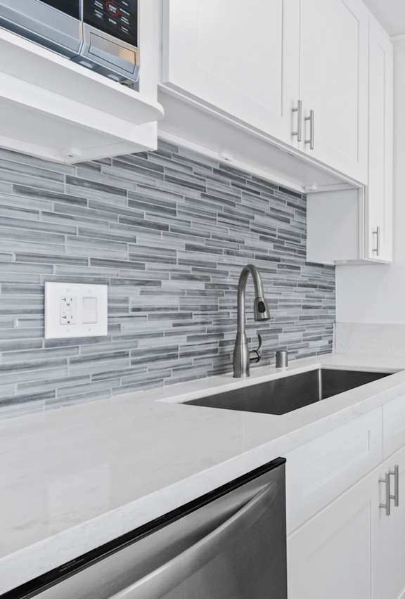 a kitchen with white cabinets and a stainless steel refrigerator