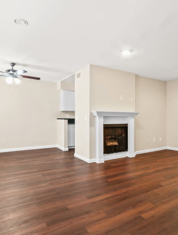 an empty living room with a fireplace and a ceiling fan