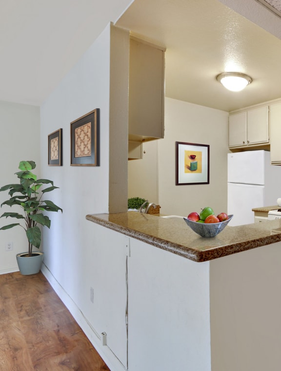 a kitchen with white cabinets and a counter top with a bowl of fruit on it