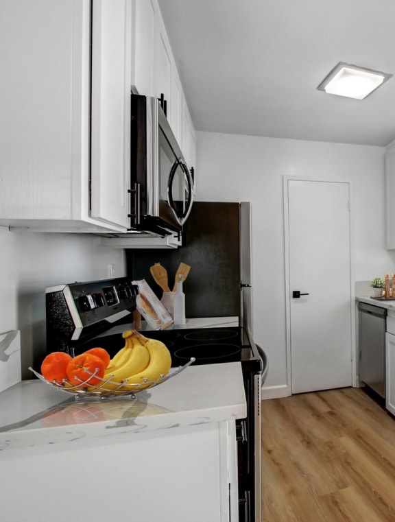 a kitchen with white cabinets and a bowl of fruit on the counter