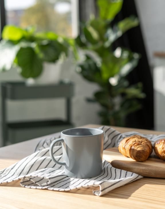 a cup of coffee and croissants on a wooden cutting board on a kitchen table