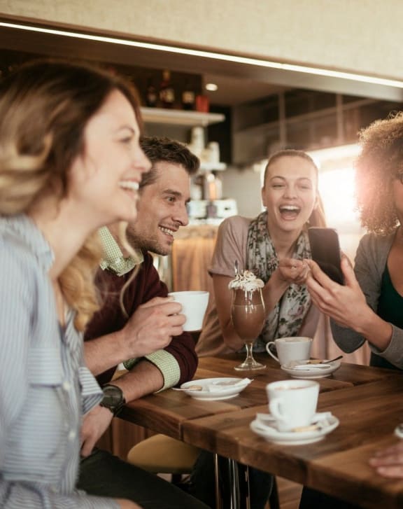 a group of people sitting around a table talking and laughing