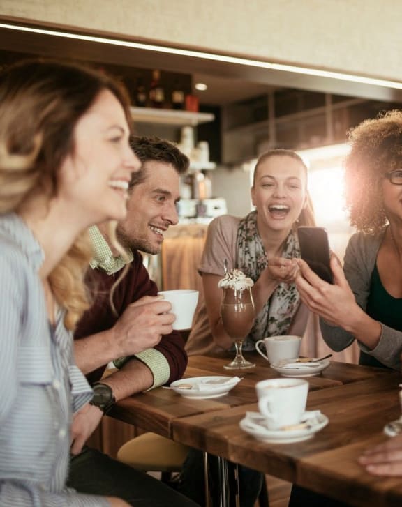 a group of people sitting around a table talking and laughing