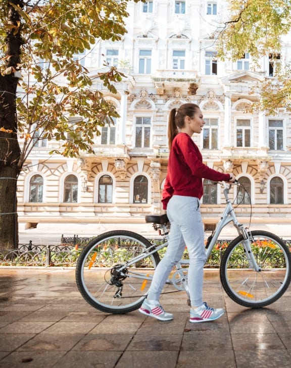 a woman walking her bike in front of a building