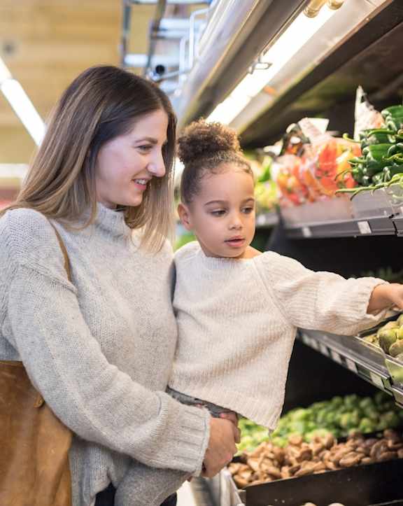 A woman and a child are shopping for produce.