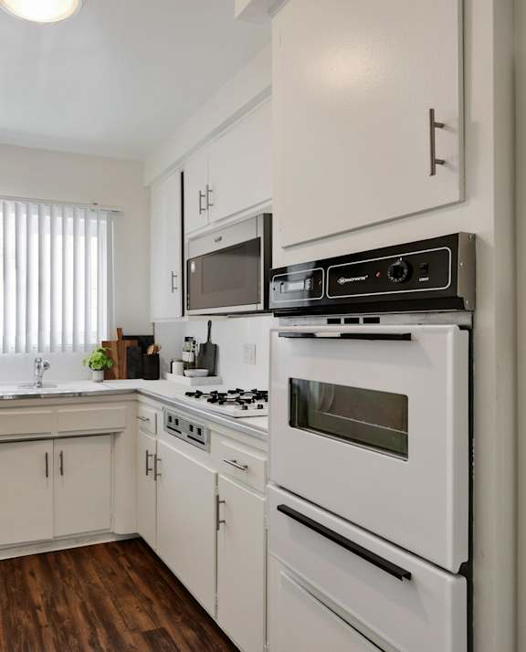 an empty kitchen with white appliances and white cabinets