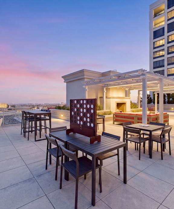 A patio with a table and chairs overlooking a cityscape at dusk.