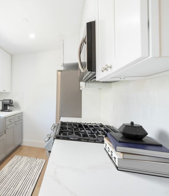 a white kitchen with stainless steel appliances and a window