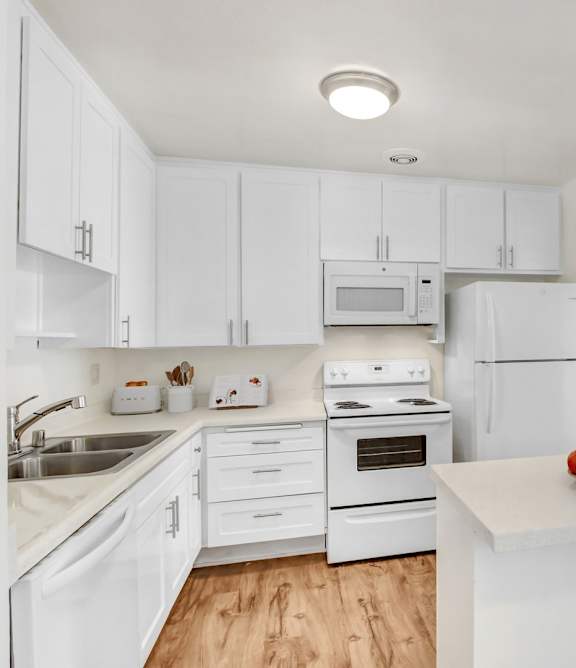 A kitchen with white cabinets and appliances.