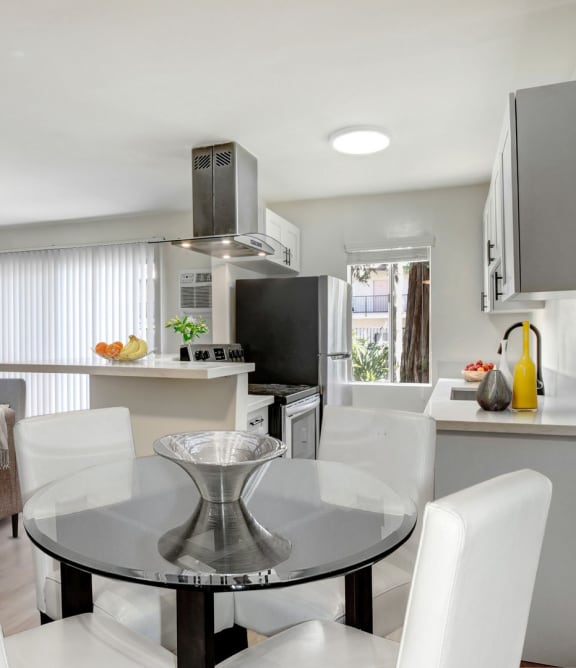 a kitchen and dining room with white chairs and a glass table
