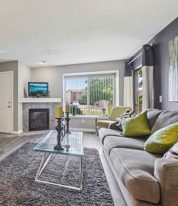 A modern living room with a glass coffee table and a grey sofa.
