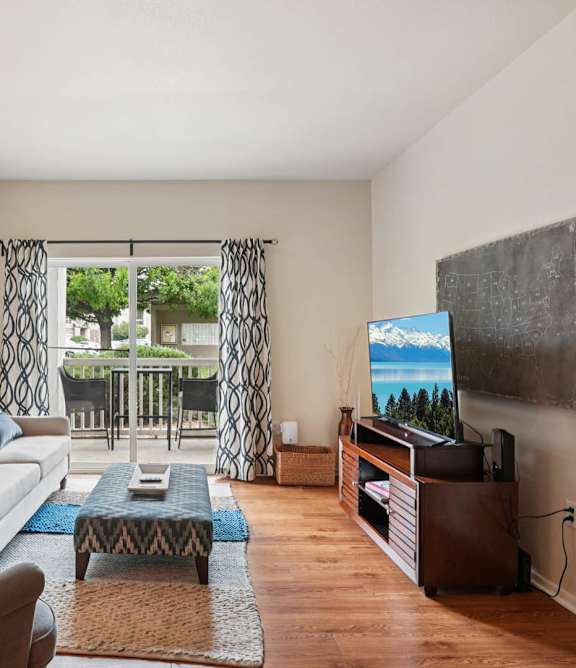 A living room with a couch, chairs, a coffee table, and a television at Heritage at Stone Mountain, Northglenn, CO 80233