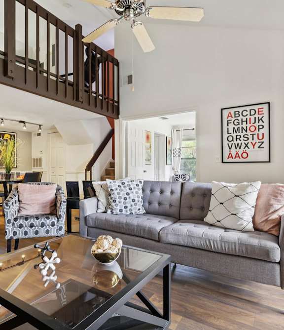 A living room with a grey couch and a glass coffee table at Whisper Lake Apartments, Winter Park, 32792