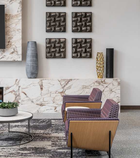 A living room with a fireplace, a sofa, a chair, and a table.at The Edison at Woodbury, Woodbury Minnesota