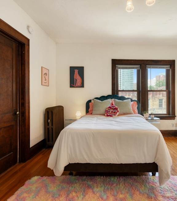 A bedroom with a bed, a chair, and a window.
