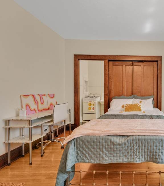 A bedroom with a bed, chair, and window.